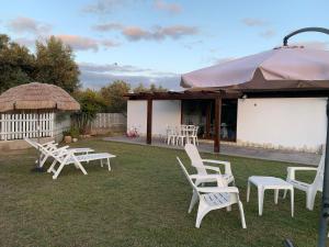 a group of white lawn chairs and an umbrella at Villa Harmony in Quartu SantʼElena