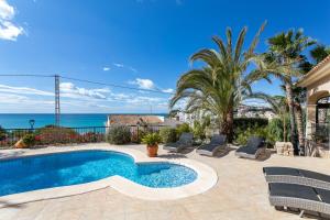 a swimming pool with chairs and the ocean in the background at Villa Mara in El Campello