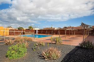 a swimming pool with umbrellas and plants in a resort at Villa Dayely in Corralejo