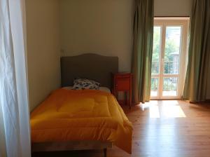 a bedroom with a bed with an orange blanket and a window at Maison L'oustal Du Lévéjac in Saint-Rome-de-Tarn