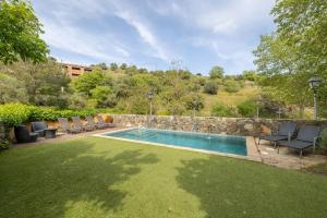 a swimming pool in a yard with chairs and a retaining wall at Casa Argentera Full House in Argentera