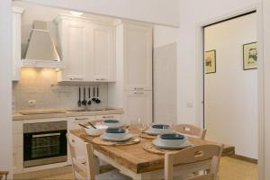 a kitchen with a wooden table with chairs and a kitchen with white cabinets at Brezza Marina Apartment in San Vincenzo +22 photos