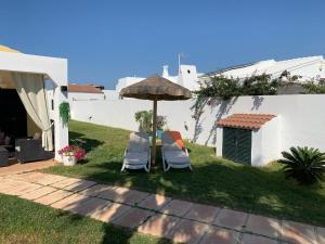 a patio with two chairs and an umbrella at Chalet con piscina en Menorca in Cala en Bosc