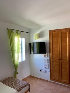 a bedroom with a tv on the wall and a window at Chalet con piscina en Menorca in Cala en Bosc