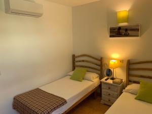 a bedroom with two beds and a night stand with a lamp at Chalet con piscina en Menorca in Cala en Bosc +23 photos