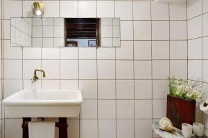 a white tiled bathroom with a sink and a mirror at Mother's House in Calheta +18 photos
