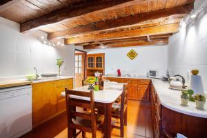 a kitchen with wooden cabinets and a table with chairs at Mother's House in Calheta
