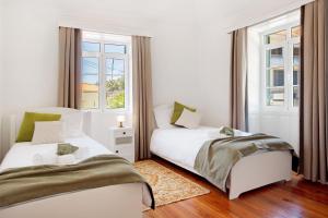 two beds in a white room with two windows at Mother's House in Calheta