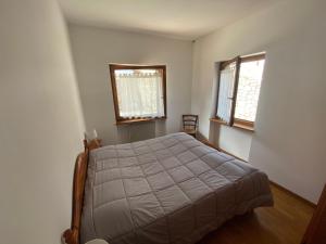 a bedroom with a bed and two windows at Residence Malibu Appartamento 2 in Falcade