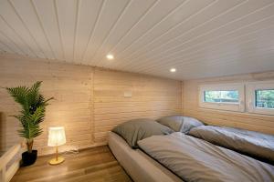 two beds in a room with wooden walls and a ceiling at Tiny House Nr 1 in Schwielowsee