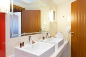 W łazience znajdują się 2 białe umywalki i lustro. w obiekcie Akrata Beach Hotel w mieście Akrata +35 zdjęć