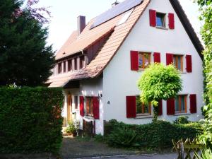 a white house with red shutters and a tree at Ferienwohnung Lahr in Lahr
