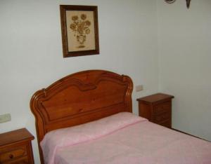 a bed with a wooden headboard and two night stands at Casa Lopez San Martín in San Martín del Castañar +12 photos