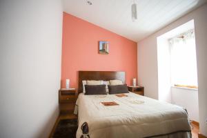 a bedroom with a large bed with an orange wall at Casa do Avô - Alojamento Sortelha in Sortelha