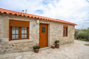 a stone house with a wooden door and two plants at Casa do Avô - Alojamento Sortelha in Sortelha