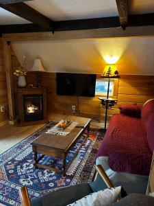 a living room with a couch and a table and a tv at Red Sleigh Chalet - Campton in Campton