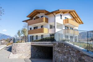 a white building with wooden balconies and a stone wall at Sunnig Apartment Abendsonne in Vollan