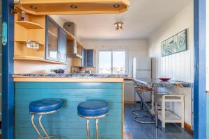 a blue kitchen with a counter and stools at Logement vue mer à 50m de plage in Barbâtre