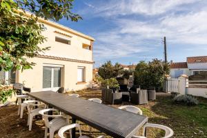 a picnic table and chairs in a yard with a house at Logement vue mer à 50m de plage in Barbâtre