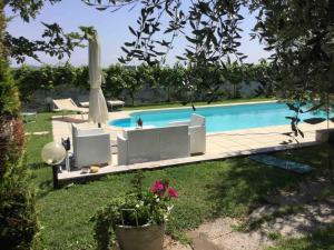 a swimming pool with chairs and an umbrella at Suite Al Pian Apartment in I Gugi