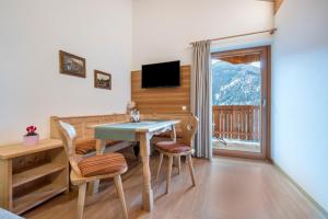 a dining room with a table and chairs and a television at Raffreiderhof Apt Zirbe in Luson