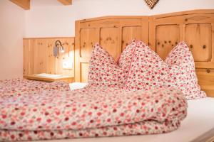 a bed with red and white pillows on it at Raffreiderhof Apt Zirbe in Luson