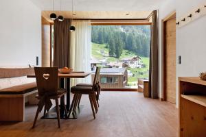 a dining room with a table and a large window at Daunëihof in Selva di Val Gardena