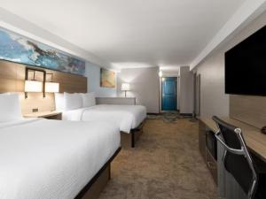 a hotel room with two beds and a flat screen tv at Garner Hotel Virginia Beach North by IHG in Virginia Beach