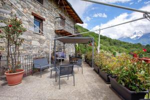 a patio with chairs and potted plants and a building at La Casa Di Pasky in Roisan
