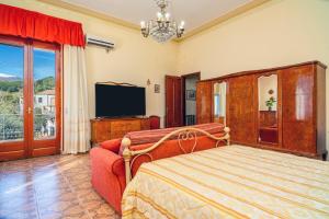 a bedroom with a bed and a tv and a couch at Il Comandante in Piedimonte Etneo
