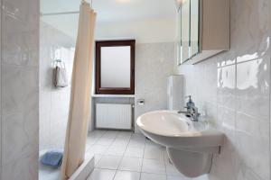 a white bathroom with a sink and a window at Urlaub Ostholstein in Stockelsdorf +10 photos