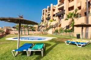 two lounge chairs and an umbrella next to a swimming pool at Apartment Coto Real in Manilva