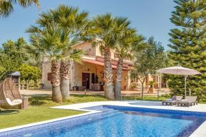 a villa with a swimming pool and palm trees at Es Vinyo in Biniali
