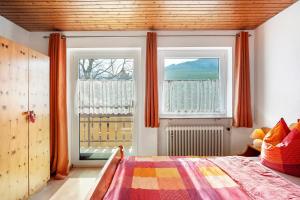a bedroom with a bed and two windows with orange curtains at Ignazhof in Horben