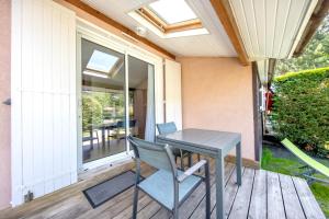 a table and chairs on a porch with a window at Chalet dans résidence piétonne in Hourtin