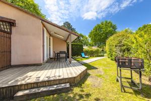 a wooden deck with a table and chairs on it at Chalet dans résidence piétonne in Hourtin