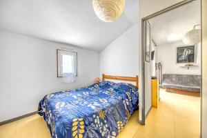 a bedroom with a bed with a blue comforter at Chalet dans résidence piétonne in Hourtin