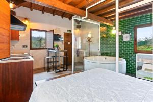 a bathroom with a tub and a kitchen with green tiles at La Manzana in Candamin