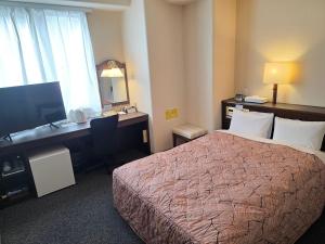 a hotel room with a bed and a desk with a computer at Nobeoka Urban Hotel in Nobeoka