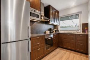 a kitchen with wooden cabinets and a stainless steel refrigerator at Ferienhaus Pfanne in Hennstedt
