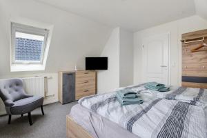 a bedroom with a bed and a chair and a television at Ferienhaus Pfanne in Hennstedt