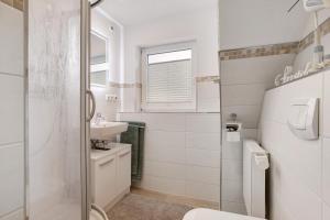a white bathroom with a sink and a toilet at Ferienhaus Pfanne in Hennstedt +18 photos