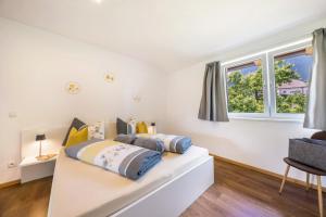 a bedroom with two beds and two windows at Angerblick Apartment in Appiano sulla Strada del Vino