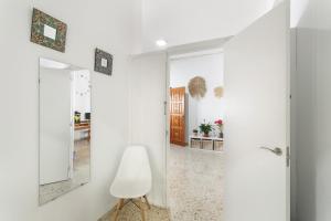 a white hallway with a mirror and a chair at Casa Mar Azul Arinaga in Arinaga