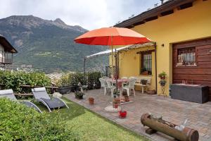 a patio with an umbrella and a table and chairs at La casa di Alice in Gignod