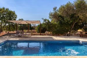 a swimming pool with a table and chairs and an umbrella at Finca Es Turo in Santanyi