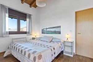 a white bedroom with a bed and two lamps at Picuastur in Cangas de Onís