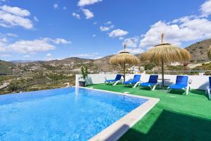 a swimming pool with blue chairs and umbrellas at Villa Joya del Mediterraneo in Almuñécar
