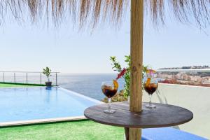 two wine glasses sitting on a table next to a swimming pool at Villa Joya del Mediterraneo in Almuñécar