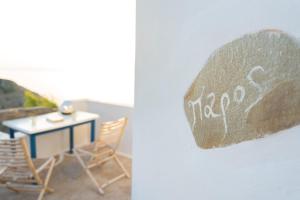 a sign on a wall with chairs and a table at Paros - Sikinos Sunset in Sikinos